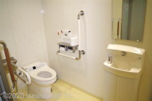 2階車いす対応トイレ　入口入って左奥に、よこ置きに便器。便器に向かって右側にＬ型固定手すり、左側にＵ型可動手すり