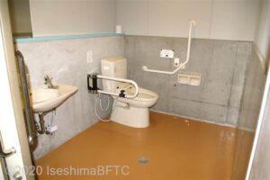 相差かまど車いす対応トイレ内部　入口からみて左奥に、よこ置きに便器。入口からみて左手前に洗面台