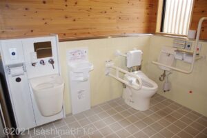 面白展望台　車いす対応トイレ大　便器に向かって右側にL型固定手すり、左側にU型可動手すり　便器の左にベビーチェアとオストメイト