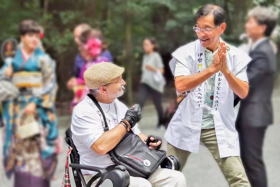 車いすの男性に参拝方法を教えるボランティア