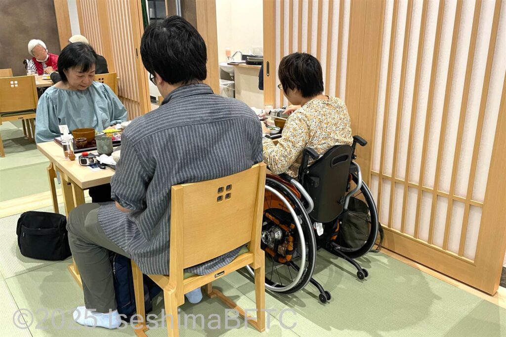 車いすのままで食事しやすい高さのテーブルで食事をいている写真