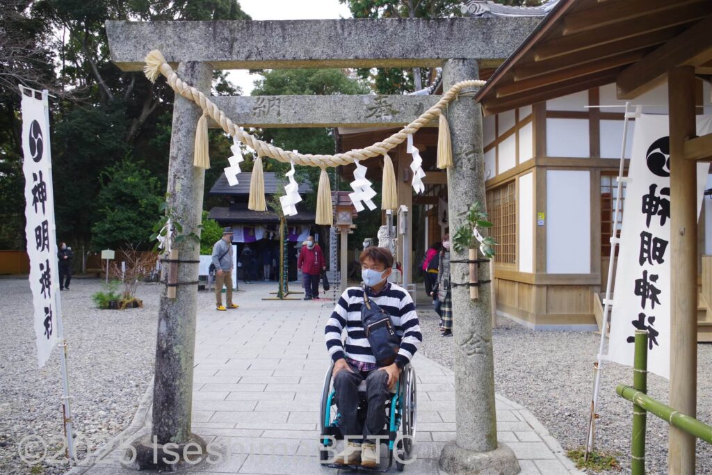 石畳の上を車いすで鳥居をくぐる