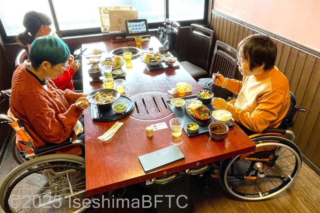 車いす利用者2名を含む3名でテーブル席での食事の様子