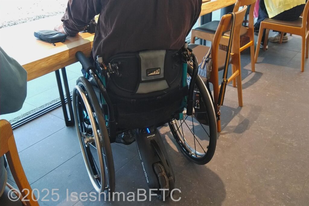 車いすでガラスに沿ったカウンター席に向かう車いす利用者