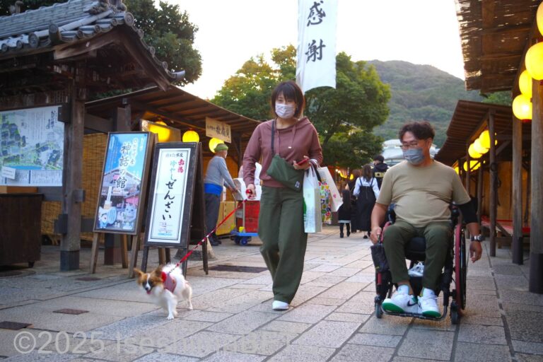 おかげ横丁を通行する車いす利用者と愛犬のリードを引いて歩く同行者