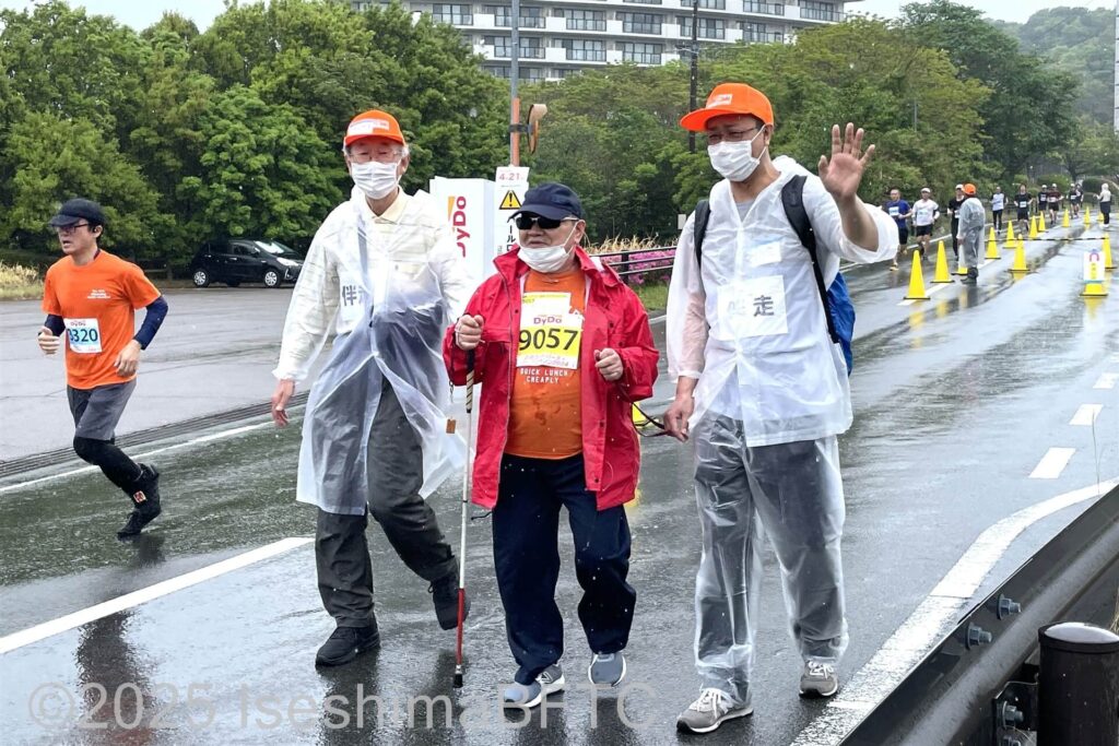 雨の中の伴走ボランティア2人歩く視覚障害選手
