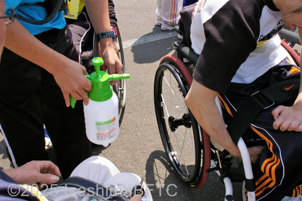 霧吹きで水をかけてもらう車いす使用者