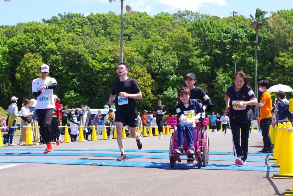 10キロのランナーと同時にゴールした簡易電動車いすの選手と家族