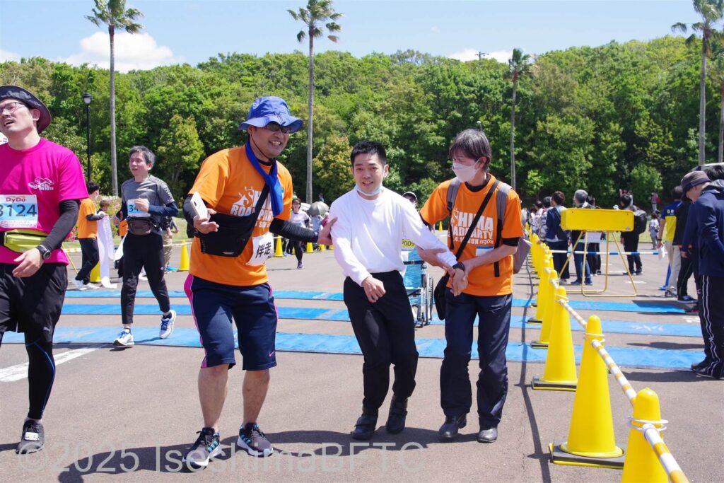 ゴール前で車いすから立ち上がり、歩いてゴールした選手と伴走ボランティア