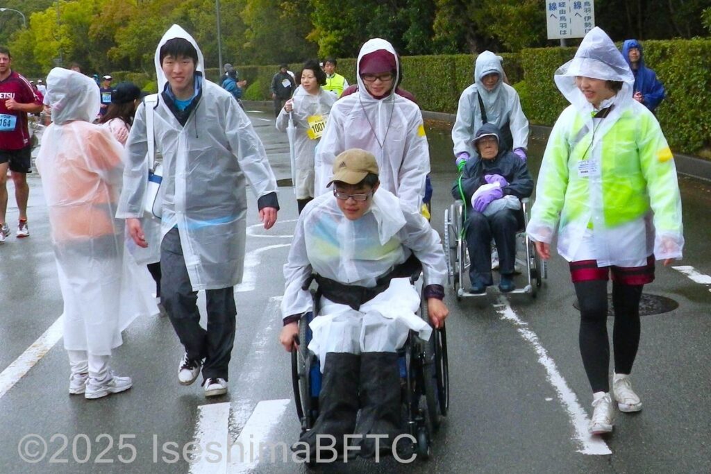 ボランティアに見守られながら力走する車いす使用者