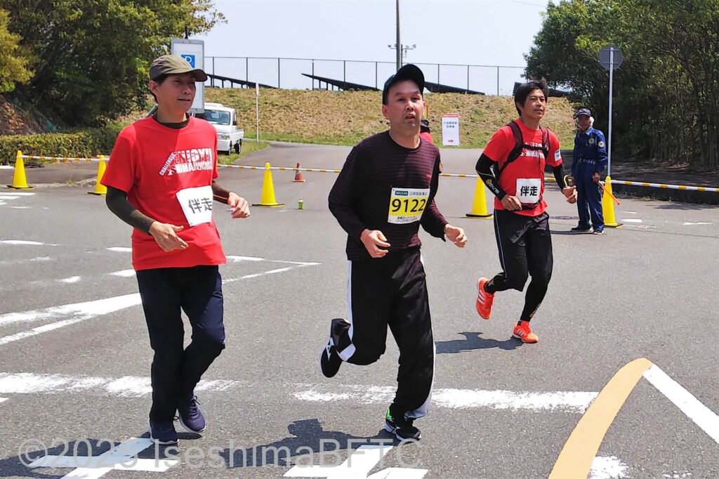 スパートする選手とそれについていくボランティア2名