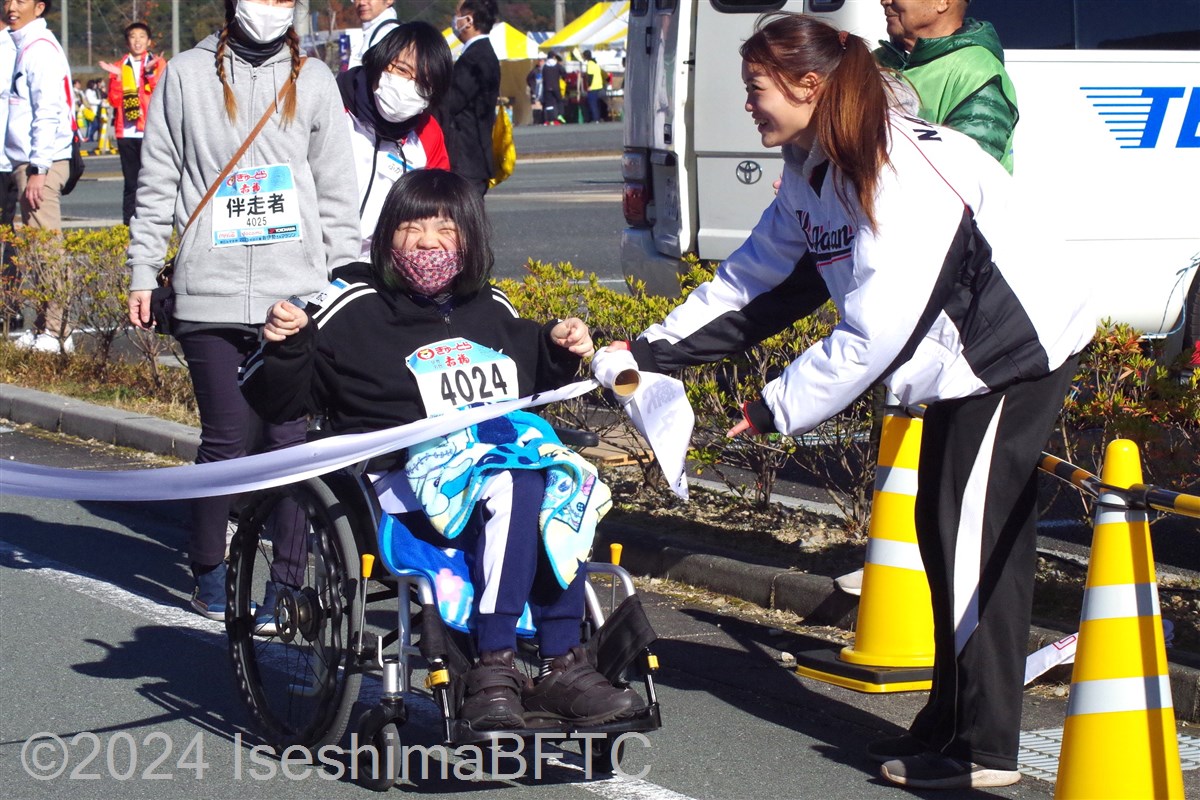 手動車いすでゴールテープを切る車いす選手