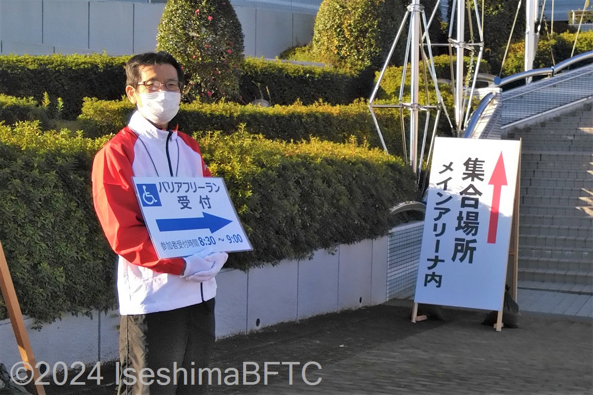 案内板を掲げて、バリアフリーラン参加者を館内へ誘導しているボランティア