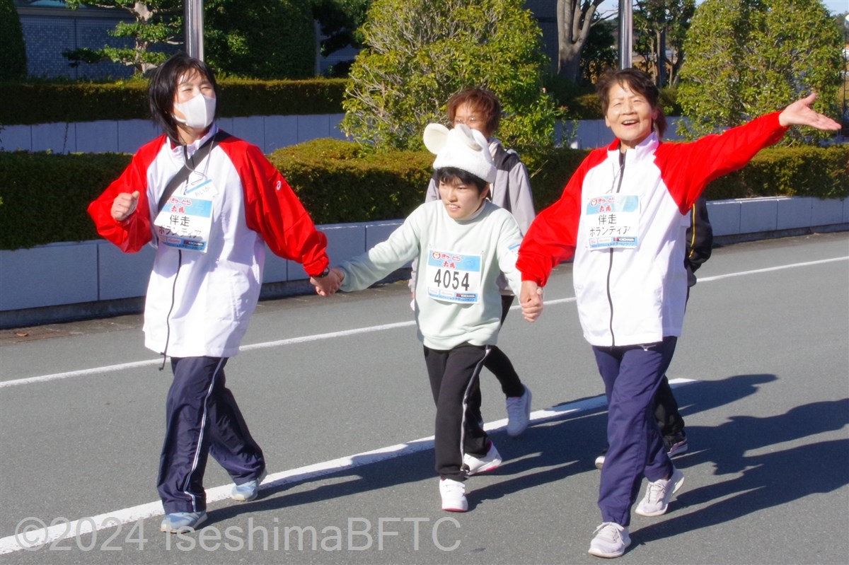 伴走ボランティア2名に両手をつないでもらって走る選手