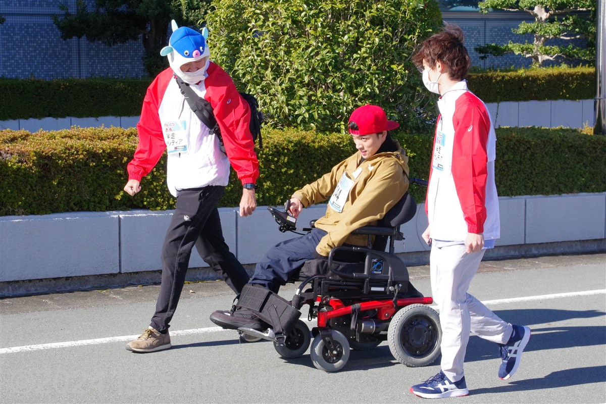電動車いすの選手を横で見守る伴走ボランティア