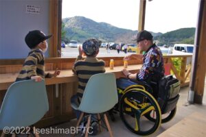 カウンターでくつろぐ車いすの男性と二人の男児。