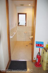 車いすトイレの入口のようす。壁には腰当たりに長い横型手すりが設置してある。