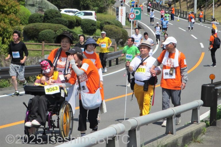 ゴールした車いすの選手と拍手を送るボランティアスタッフ