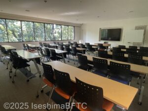講義室の室内のようす。スクール形式で、長机とイスがたくさん置かれている。