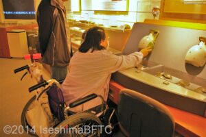 土器復元パズルを車いすの女性が触っているようす。