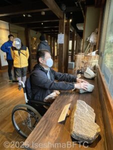 展示の石を車いすの男性が触っているようす