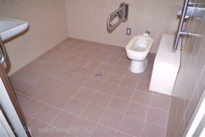車いす対応トイレ内部　引戸正面に、たて置きに便器あり
