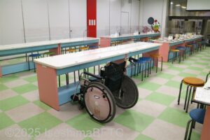 テーブル前に車いすが置かれているようす。車いすの人でも体験しやすい高さなのがわかる。