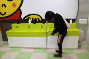 洗面台の高さをメジャーで図る調査員のようす。洗面台は黄緑色。