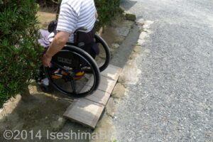 土間から後庭への通路のようす。段差解消の板の上を車いすの男性が下りているようす。