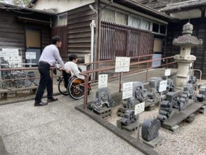 車いすの方の入館用入口のようす。入口前には常設スロープが設置してあり、車いすの女性が男性の介助でスロープを上っているようす。