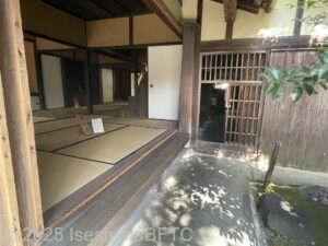 左側には開け放たれた旧宅があり、その右横には土間になっている通路が見える。