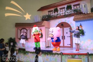 キャラクターのダンスショー。ステージ上では左端に白いスカートをはいたお姉さん、中央にホシオくん、右側にはブタの着ぐるみ、名前はブタメンの3人がダンスを踊っているようす。