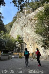 花窟神社の御神体である、そびえたつ岩を見上げているようす。