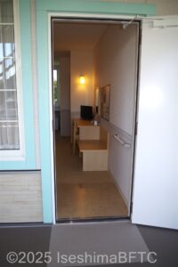 客室入り口　明かりが灯り　机と棚が見える
