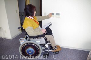 低い位置のスイッチにさわる車いす利用者