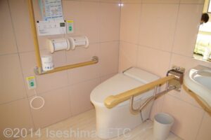 便器まわりのようす　便器に向かって右側にＩ型可動手すり、左側壁にＬ型手すり