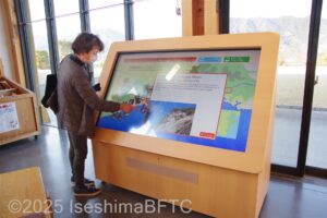 交流棟の入口にある熊野古道紹介のタッチ式ディスプレイを操作している女性のようす。