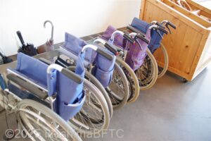 交流棟の入口に置かれている貸出車いす。4台が折りたたまれて置かれている。
