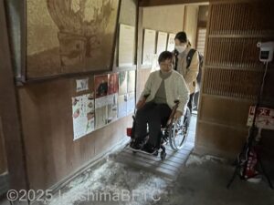 屋敷の玄関から奥に続く土間を車いすの女性が通っているようす。