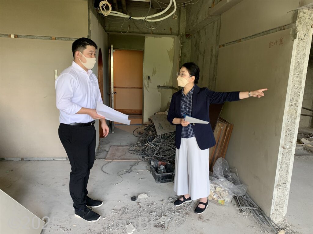 工事中の客室で、旅館の社長とスタッフがバリアフリー改修について打ち合わせをしているようす。