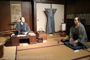 江戸時代の庄屋を再現したジオラマ。髷を結い、羽織を着た着物姿の商人二人が会話をしているようす。
