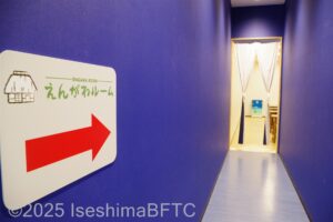 「えんがわルーム」と呼ばれる自由に使える休憩所へ向かう通路。通路はかなり細長い。壁は青色に塗られている。