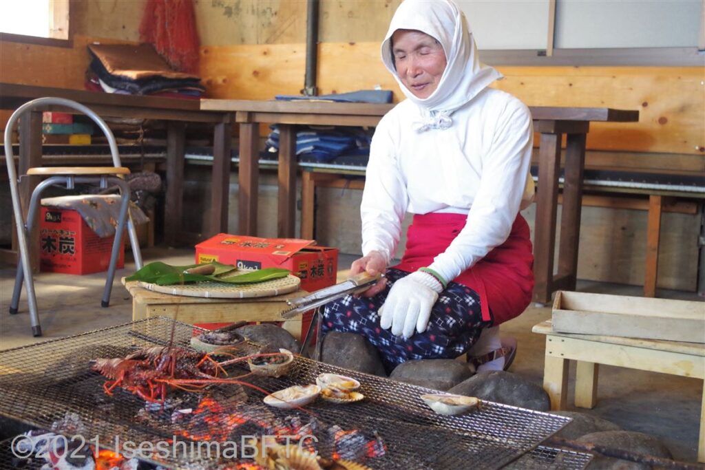 炭火で伊勢エビや貝を焼く海女さん