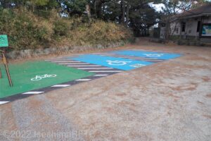 駐車場の他の区画は白線が敷いていないが、障害者専用駐車場2台分は青色で、自転車用の駐車スペースは緑色のペイントがされている。