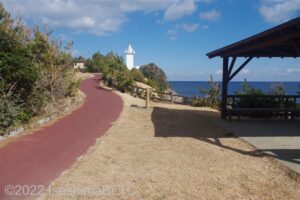 遊歩道の奥から灯台を見上げたようす。右側には東屋がある。