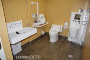 車いす対応トイレの室内のようす。便器に向かって左手にはL字手すり、右側にはU字の可動式手すりが付いている。そのほかにベビーシートとオストメイトも設置されている。