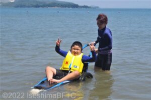 「ヒッポキャンプ」で海に入ってピースサインをしている子ども