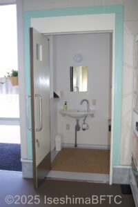 トイレの入り口ドアが開いた状態　ドア開けた正面には洗面あり　水栓方法は自動