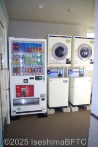 左から飲み物の自動販売機　コインランドリー2基が並ぶ