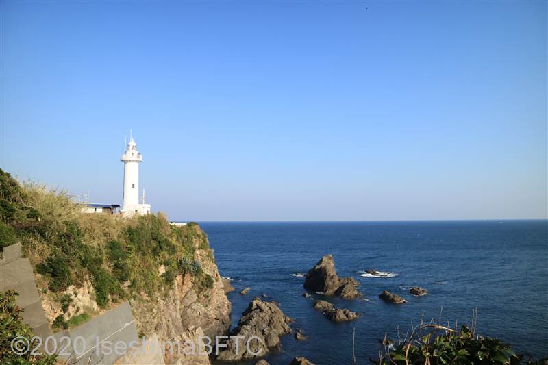 大王埼灯台の遠景。左側に見える岬の先に白い塔が建つようす